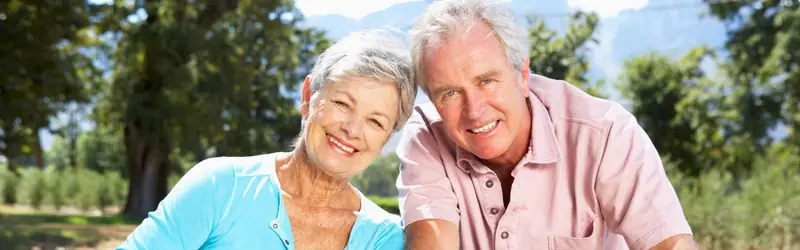 An older couple walking among park trees