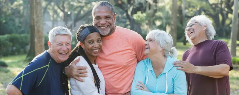 A group of older friends talking together outdoors in a park